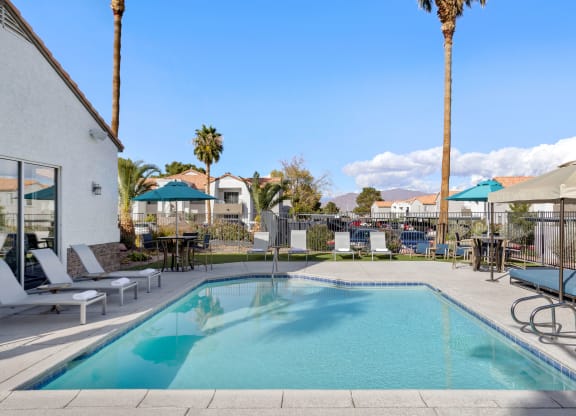 a swimming pool with lounge chairs and umbrellas at the enclave at woodbridge apartments in